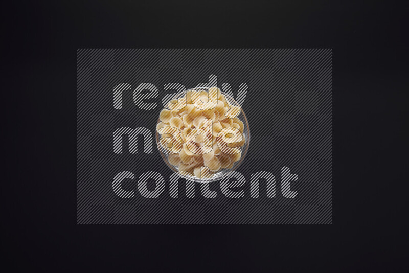 Fiocchi pasta in a glass bowl on black background