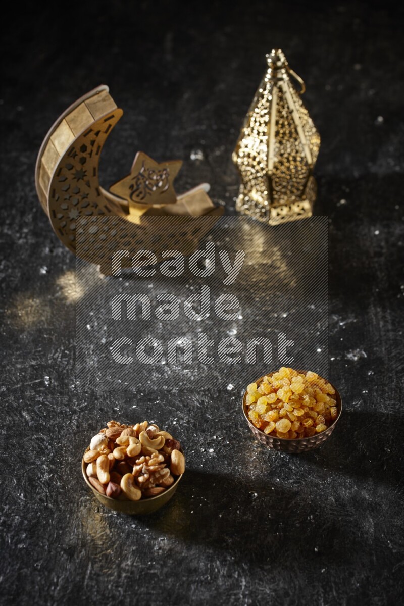 Nuts in a metal bowl with raisins beside golden lanterns in a dark setup