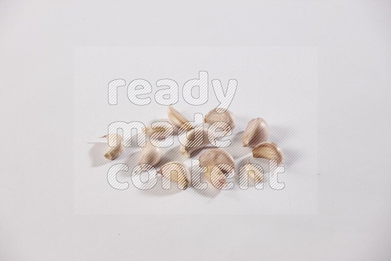 Scattered garlic cloves on a white flooring