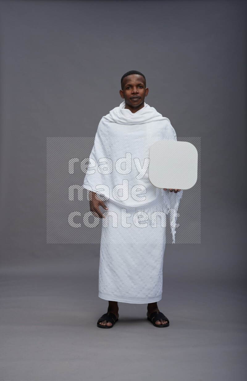 A man wearing Ehram Standing holding social media sign on gray background
