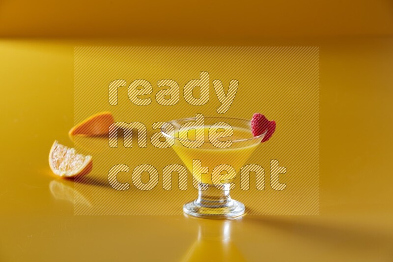 glass of orange juice with berry on yellow background