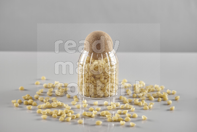 Raw pasta in a glass jar on light grey background