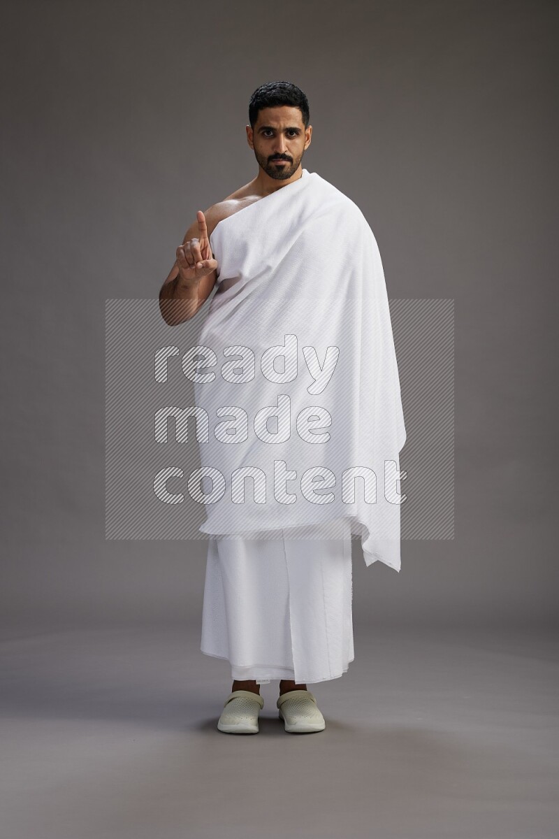 A man wearing Ehram Standing Interacting with the camera on gray background