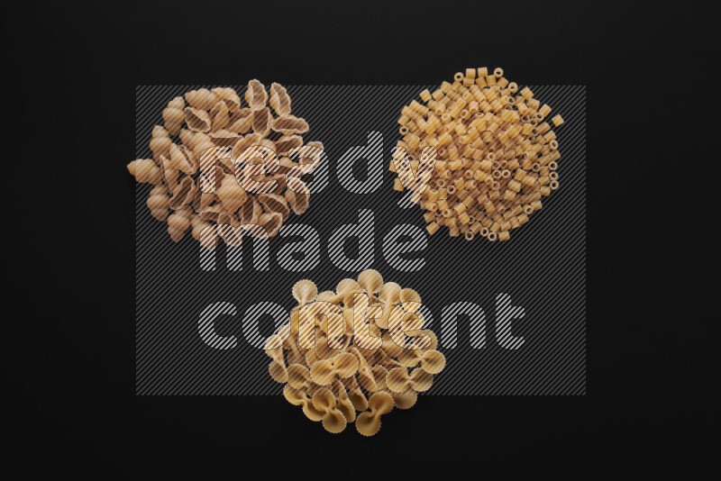 Different pasta types in bunches on black background