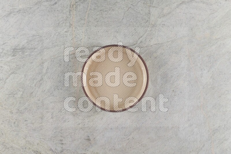 A beige pottery oven bowl on grey marble background