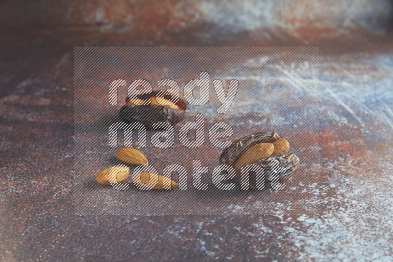 two almond stuffed madjoul dates on a rustic reddish background