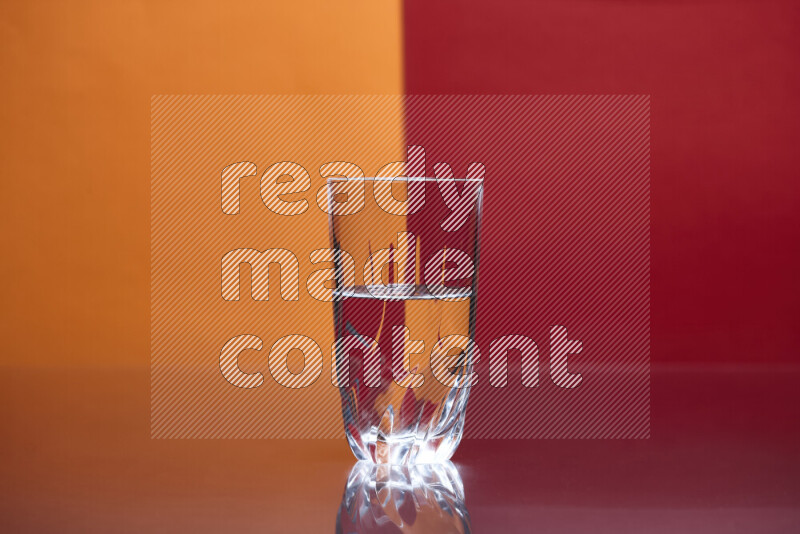The image features a clear glassware filled with water, set against orange and red background