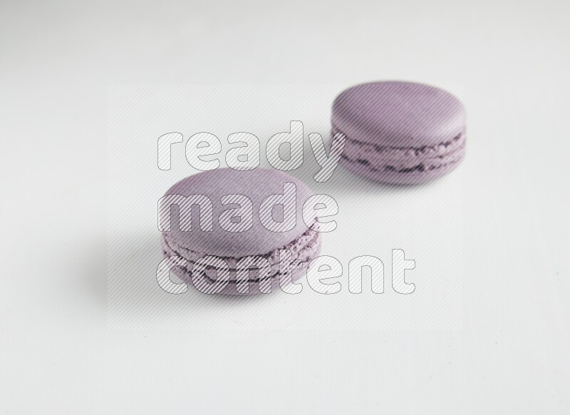 45º Shot of two Purple Blueberry macarons on white background