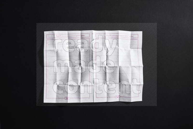 Folded notebook sheet on black background