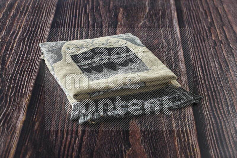A folded prayer mat with different elements such as quran and prayer beads on brown wooden background