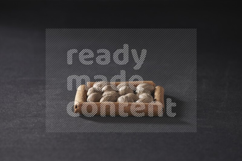 A single square of cinnamon sticks full of nutmeg on black flooring