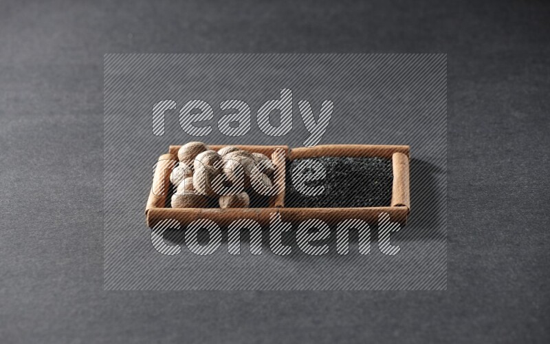 2 squares of cinnamon sticks full of black seeds and nutmeg on black flooring