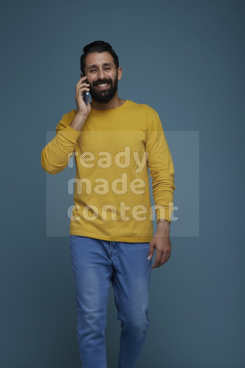 A man having a calling in a blue background wearing a yellow shirt