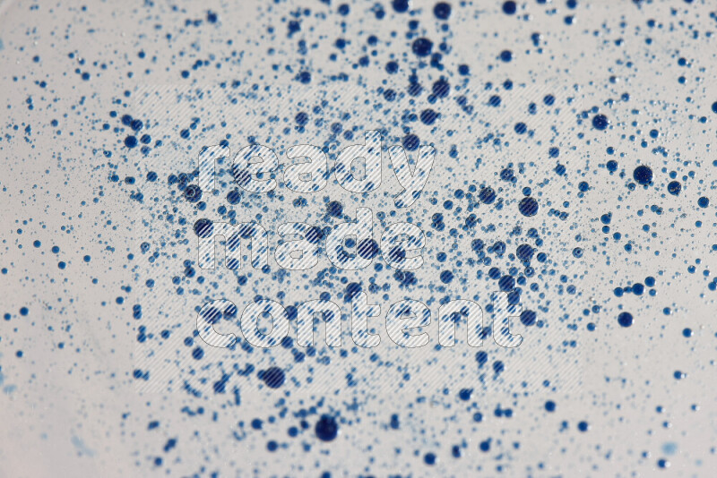 Close-ups of abstract blue watercolor drops on oil Surface on white background