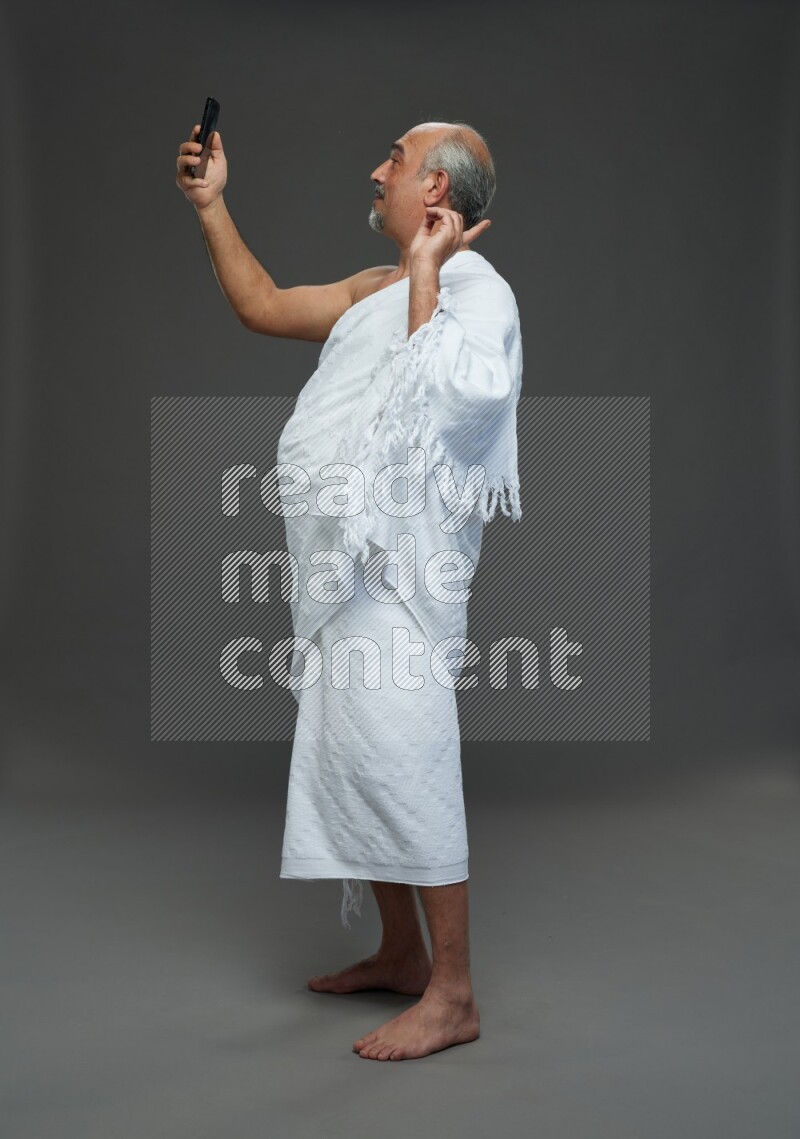 A man wearing Ehram Standing taking selfie on gray background