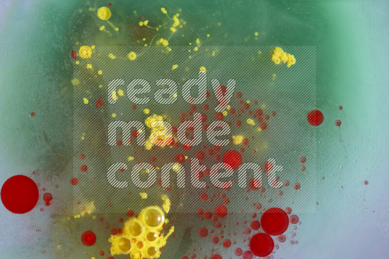 The image captures a dramatic splatter of red, green and yellow paints over the backdrop