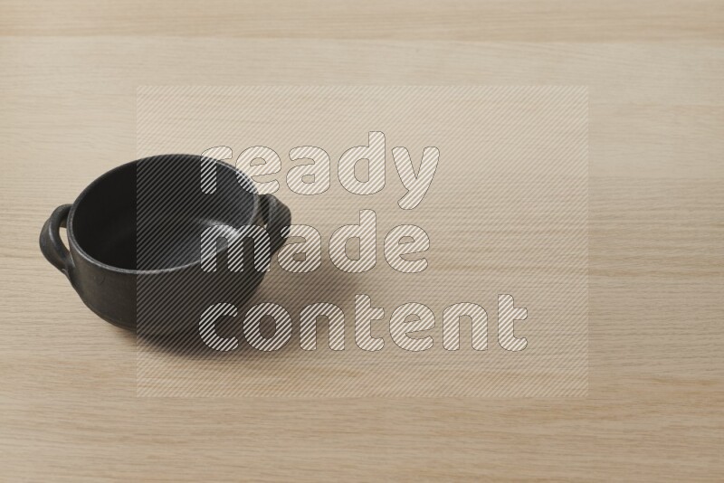 A black pottery bowl on light wooden background