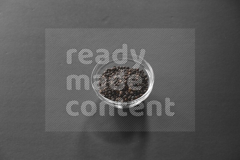 فلفل أسود في وعاء زجاجي علي خلفية سوداء