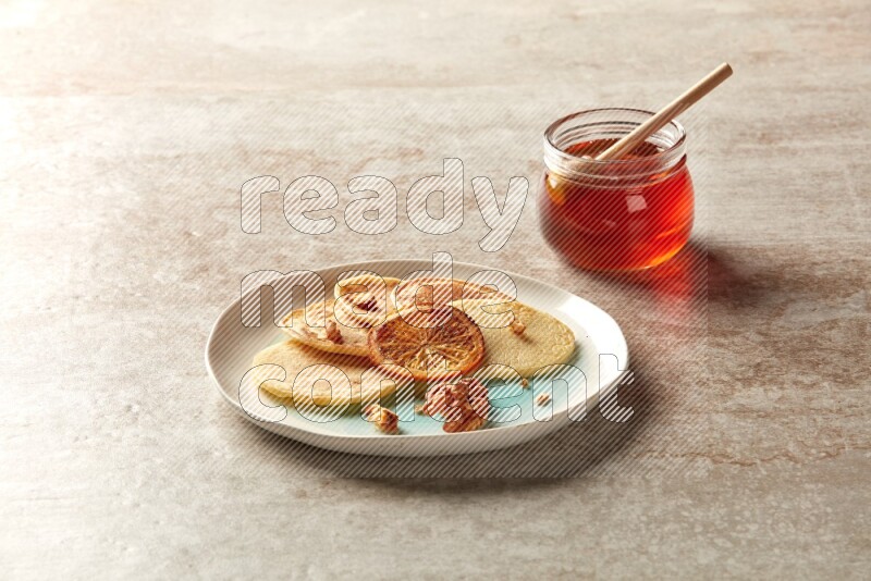 Five stacked dried orange mini pancakes in a bicolor plate on beige background