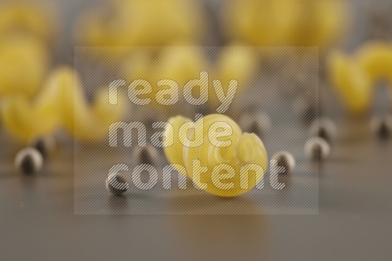 Raw pasta with different ingredients such as cherry tomatoes, garlic, onions, red chilis, black pepper, white pepper, bay laurel leaves, rosemary and cardamom on beige background