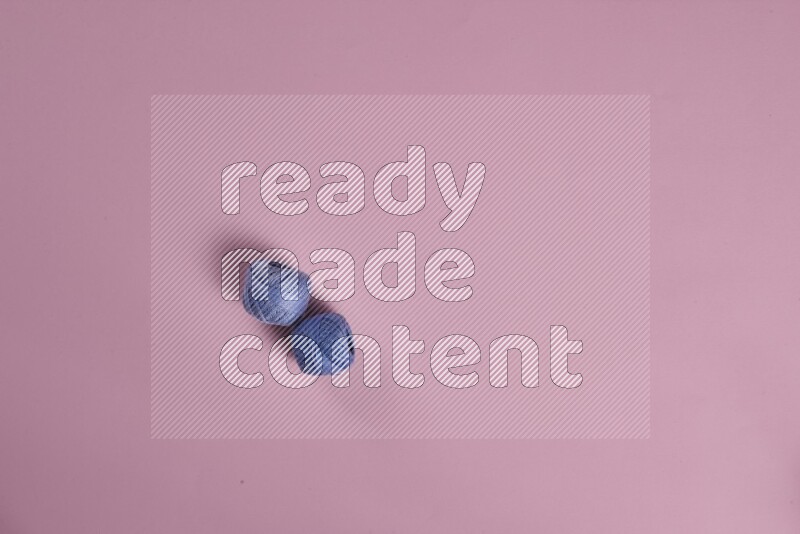 A blue collection of sewing and tailoring tools arranged on a pink background