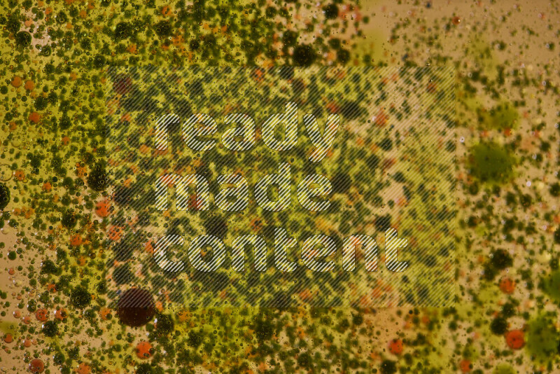 Close-ups of abstract green, black and red watercolor drops on oil Surface on yellow background