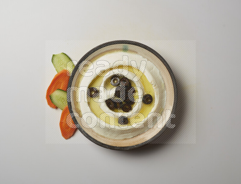 Lebnah garnished with sliced olives in a pottery plate on a white background