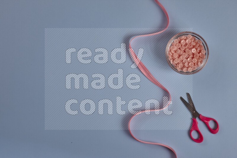 A pink collection of sewing and tailoring tools arranged on a blue background