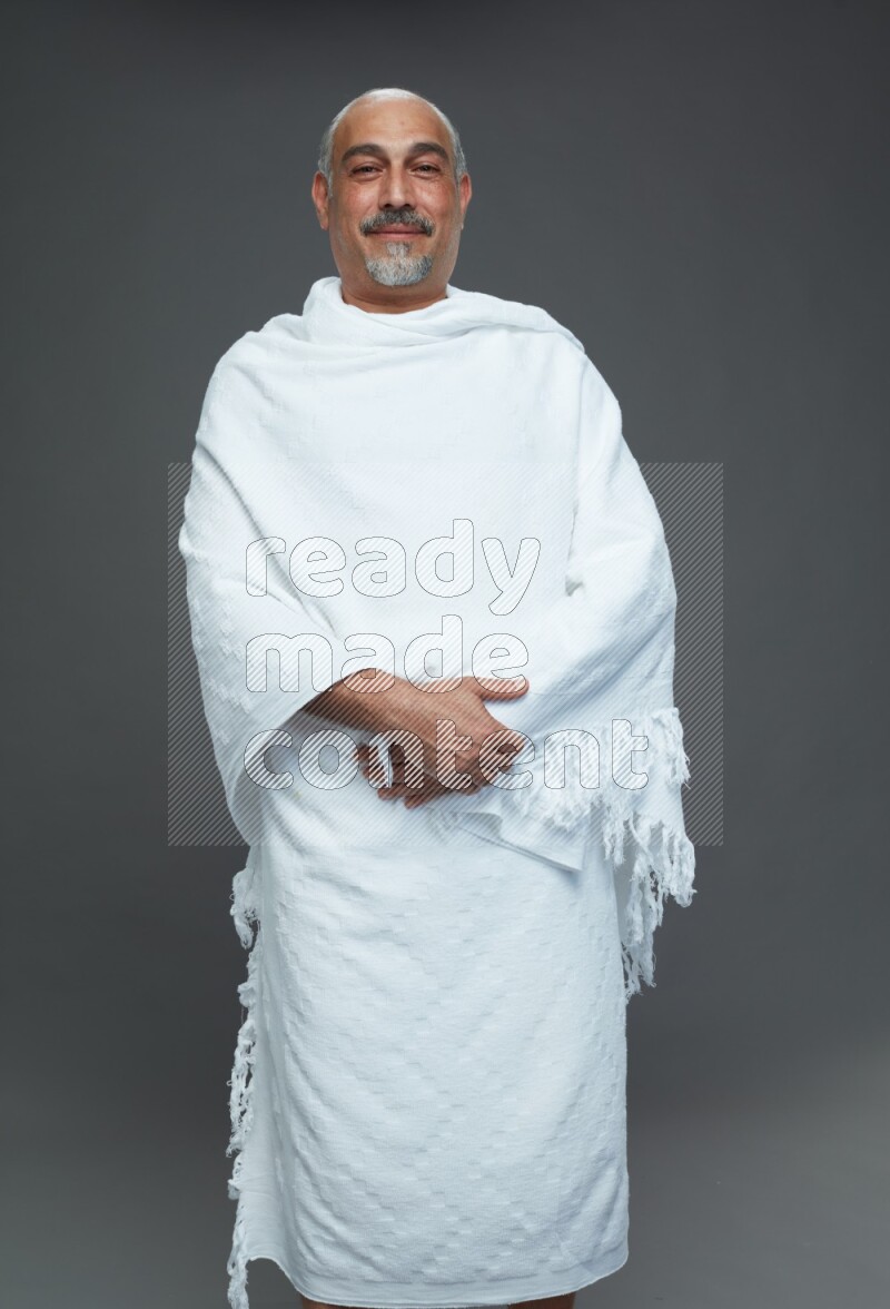 A man wearing Ehram Standing Interacting with the camera on gray background