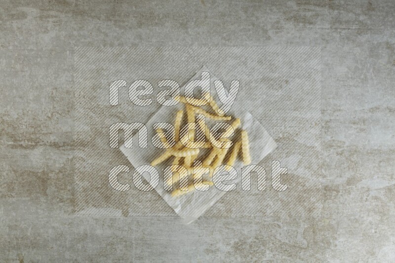 crinkle fries on parchment paper on grey textured counter top