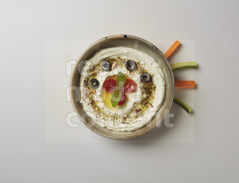 Lebnah garnished with cherry tomato, mint, olives & pine nuts in a grey pottery plate on a white background