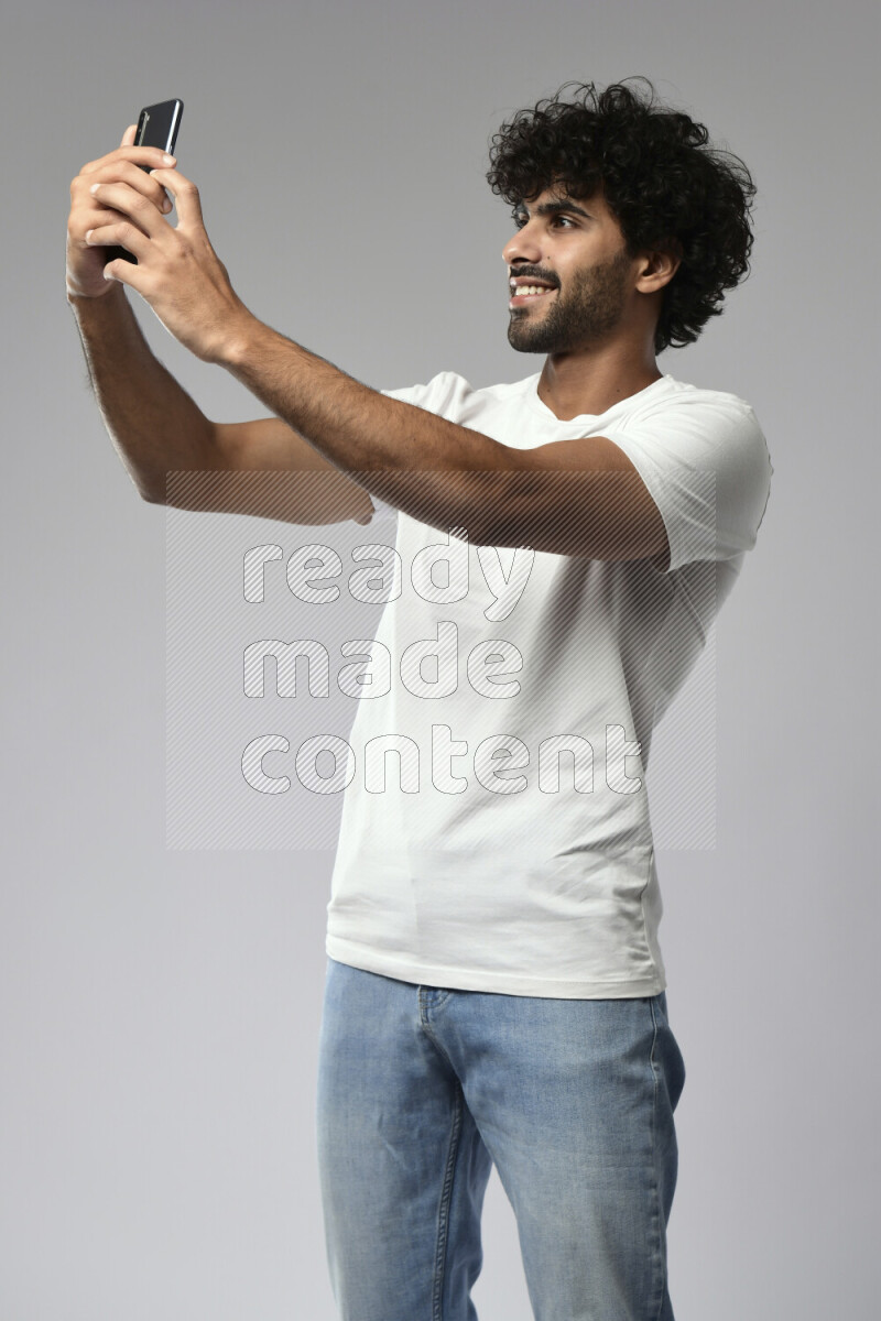 A man wearing casual standing and taking a selfie on white background