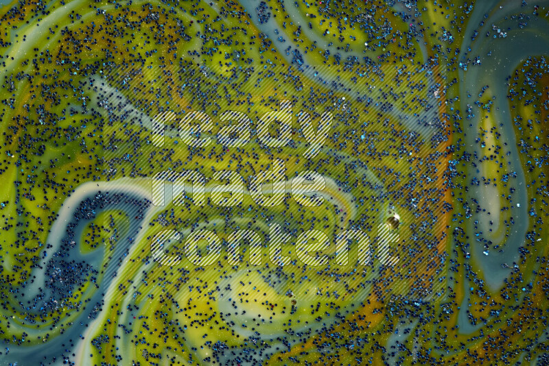 A close-up of sparkling blue glitter scattered on swirling blue and yellow background