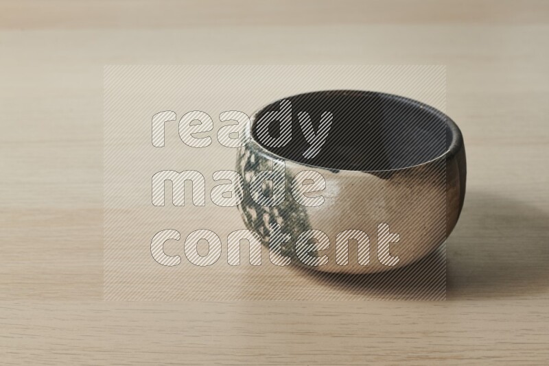 A multicolored pottery bowl on light wooden background