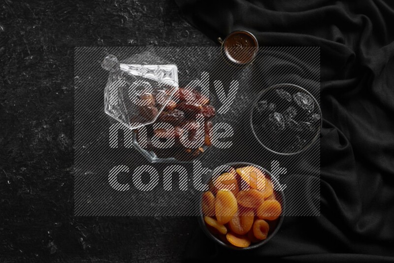 Dates in glass bowl with coffee and dried fruits in a dark setup