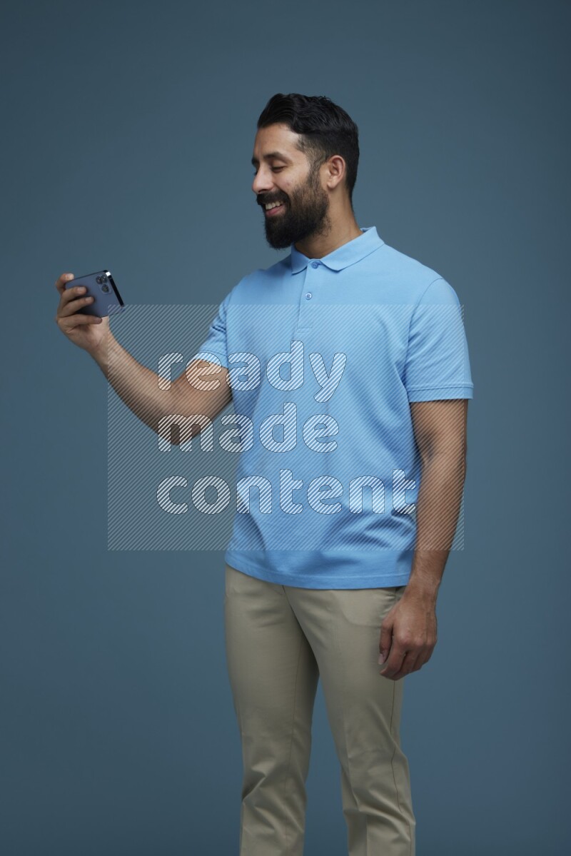 A man Watching a movie on his phone in a blue background wearing a Blue shirt