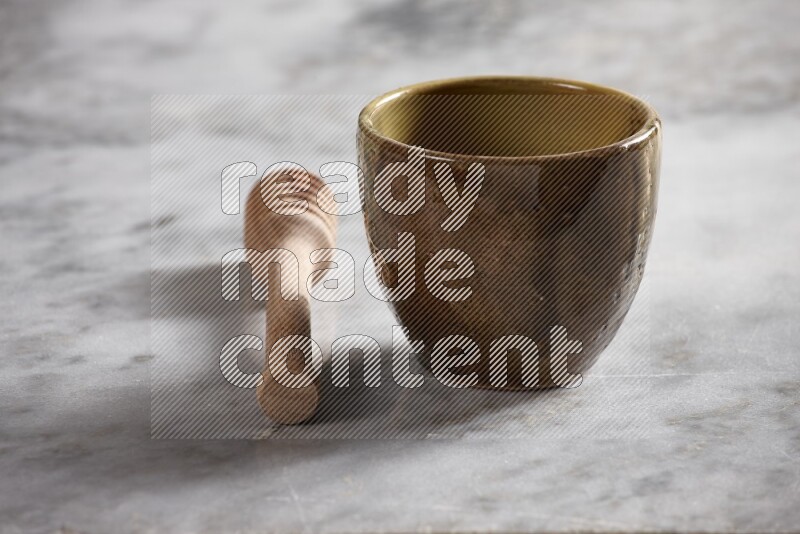 Multicolored pottery cup with wooden honey dipper on the side on grey marble background