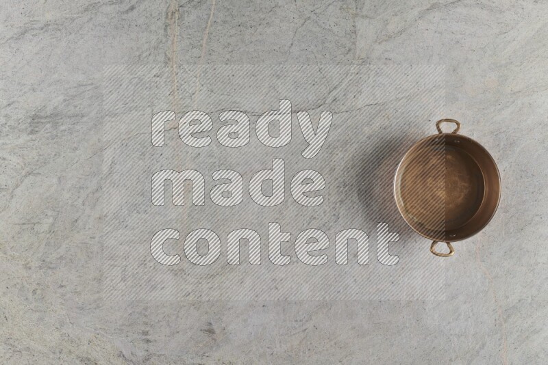 A small copper pan on grey marble background