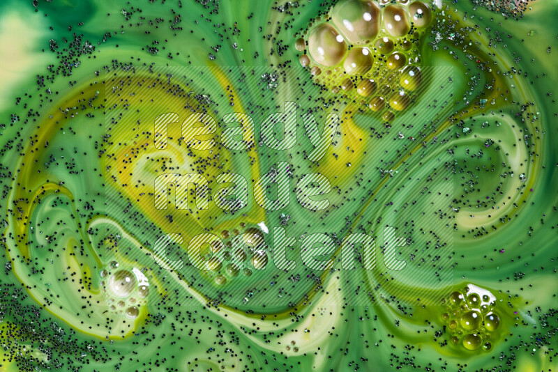A close-up of sparkling green glitter scattered on swirling yellow and green background