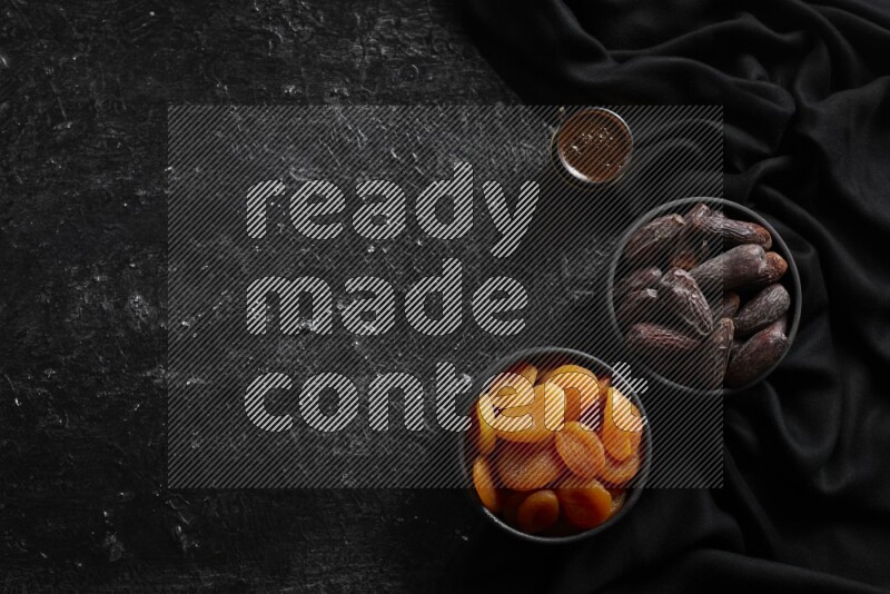 Dried fruits in pottery bowls with coffee in a dark setup