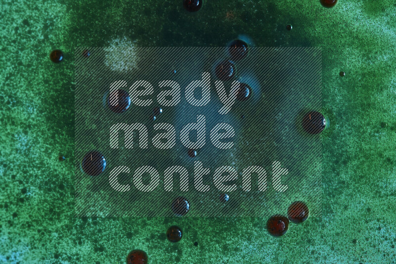 Close-ups of abstract red and green watercolor drops on oil Surface on green background