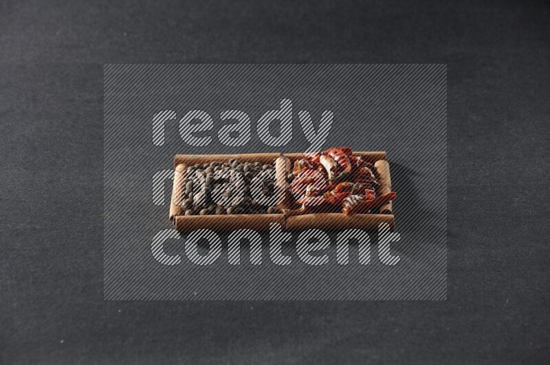 2 squares of cinnamon sticks full of chilis and allspice on black flooring