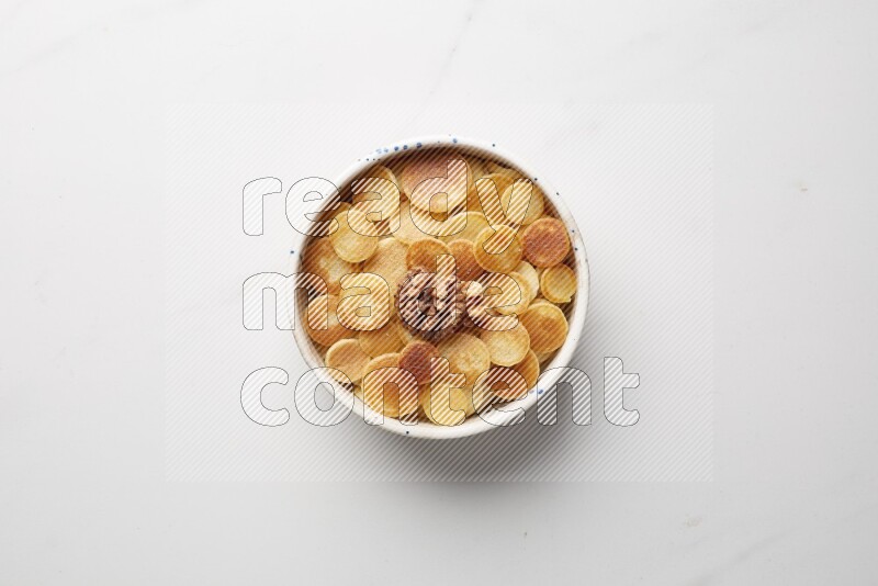 Top-view shot of walnut cereal pancakes in a round bowl on white background