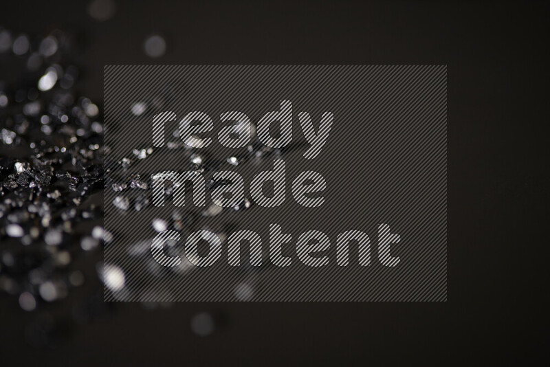 Black shimmering fragments of glass scattered on a black background