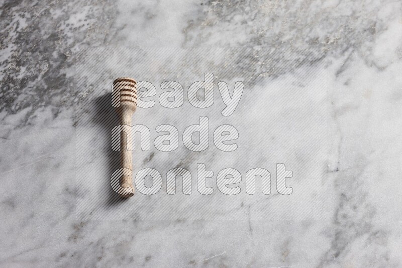 Wooden honey dipper on grey marble background