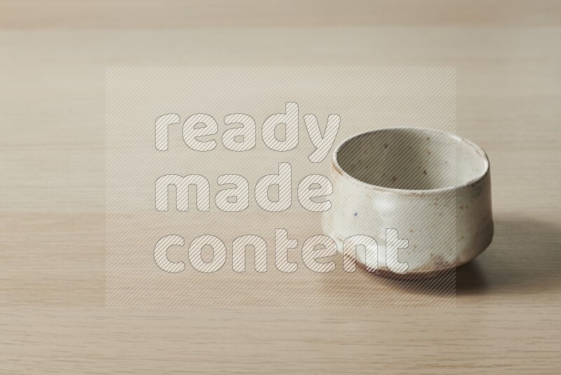 A beige pottery bowl on light wooden background