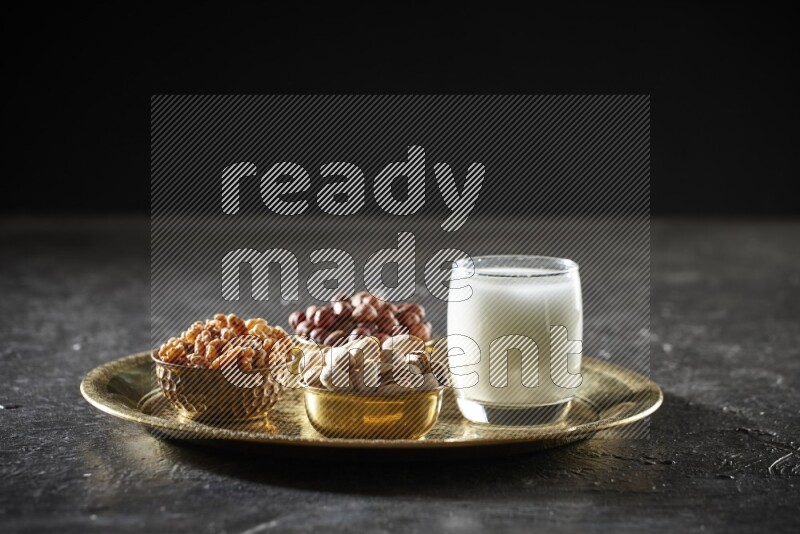 Nuts in metal bowls with sobya on a tray in dark setup