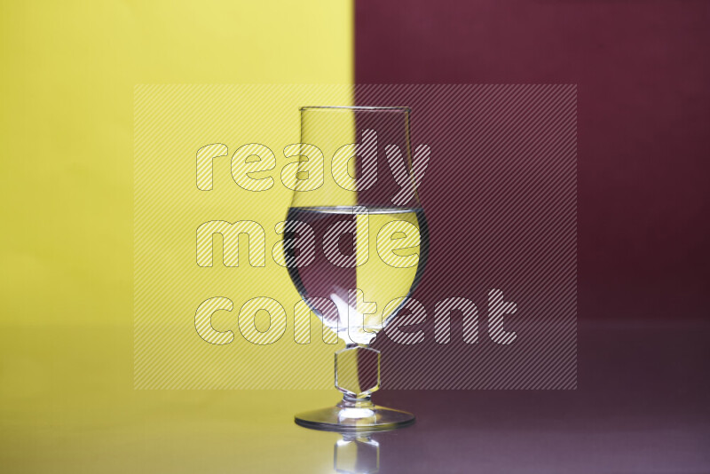 The image features a clear glassware filled with water, set against yellow and dark red background