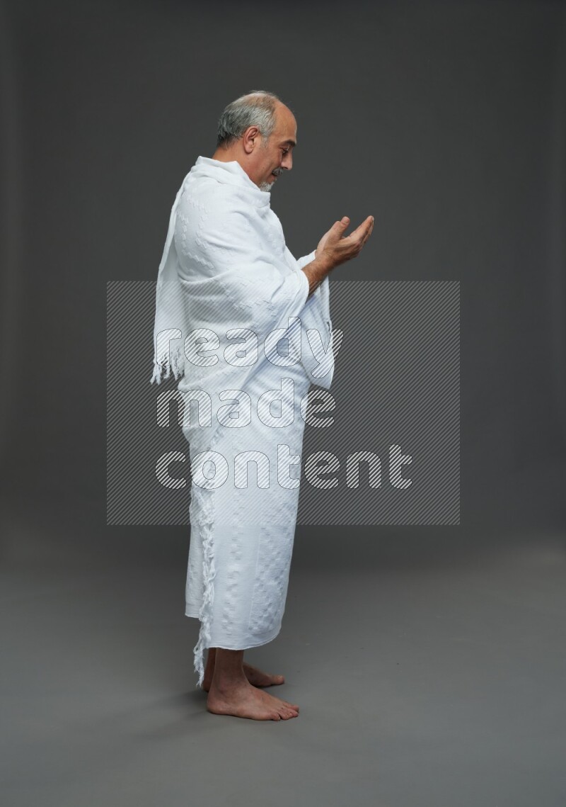 A man wearing Ehram Standing dua'a on gray background