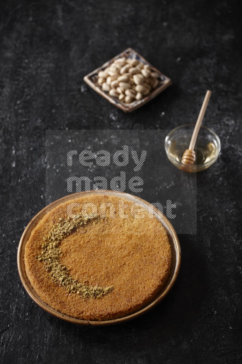 Konafa with nuts and honey in a dark setup